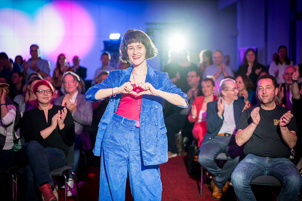Sexualexpertin Genoveva Dünzinger gewinnt bei Silent Speaker Battle in Dresden. Foto mit dem Publikum, die Speakerin formt ein Herz mit den Händen.
